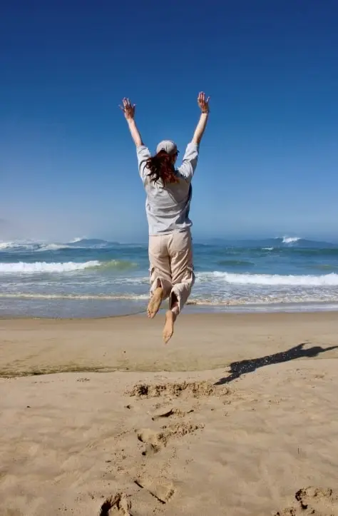 a woman jumping in the air on the beach